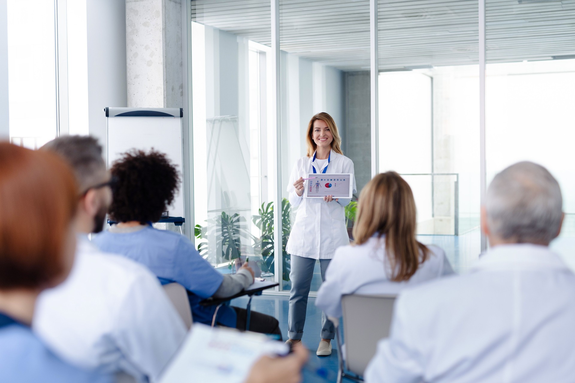 Female doctor as speaker at conference for healtcare workers, medical team sitting and listening presenter. Medical experts attending an education event, seminar in board room.